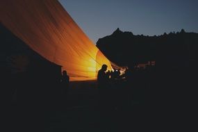silhouettes of people near the hot air balloon at night