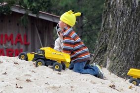 boys play with trucks on the sand