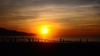 silhouettes of people on the beach at sunrise, vietnam