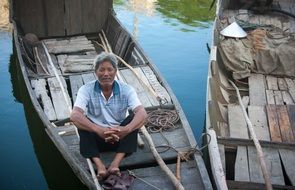 old fisherman sitting in boat on water