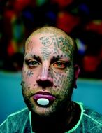 a man's face with tattoos and piercings