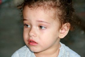 nice toddler with curly hair looks innocent