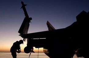 military aircraft and pilot silhouettes at sunset on background