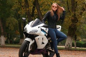 beautiful girl in a leather jacket leaned on the motorcycle