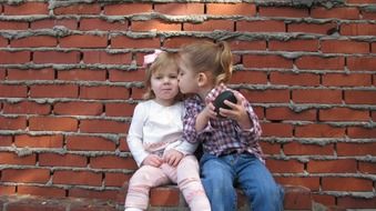 two kissing children near a brick wall