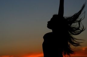 silhouette of a beautiful girl on a background of dark sunset