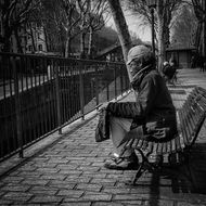 man sitting on a bench in a street of paris