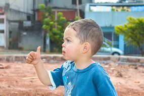 pretty child boy making thumb up gesture in ciry