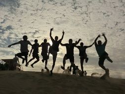 silhouettes of jumping people on the sand in the desert