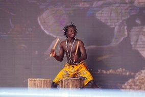 african man in colorful shirts is playing the drums