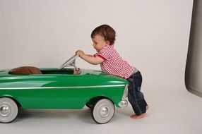 baby playing with green toy car