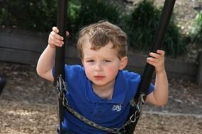 thoughtful boy on a swing close up