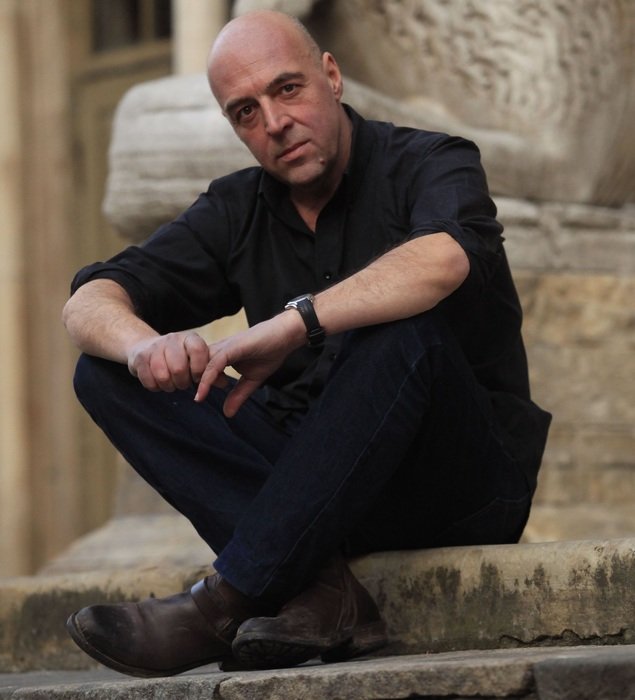 Italian is sitting on the steps in a black suit