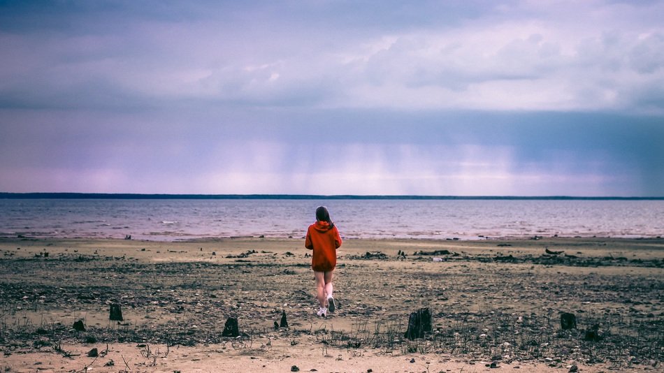 girl in a red sweater on a cloudy beach
