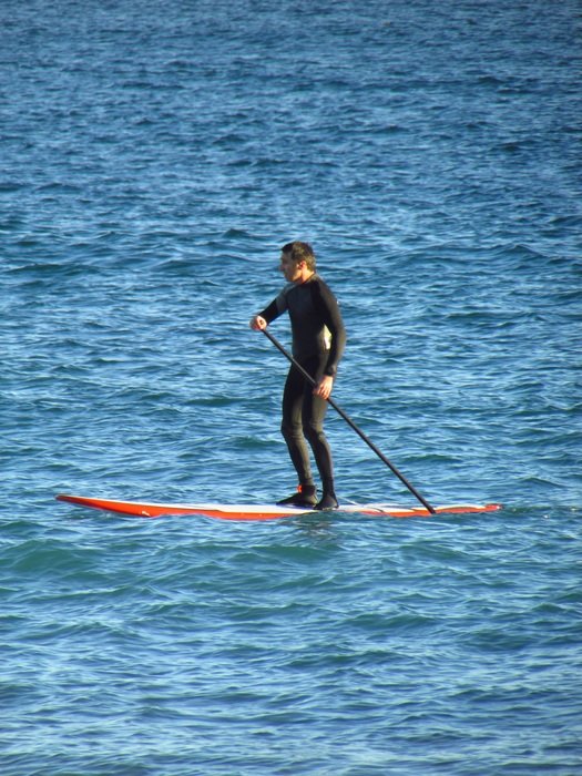 sporty man rowing on the surf in ocean