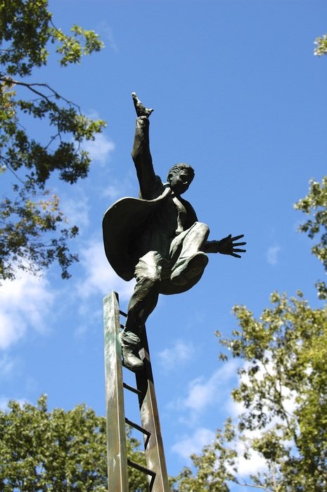 bronze statue of a man on the ladder in a park