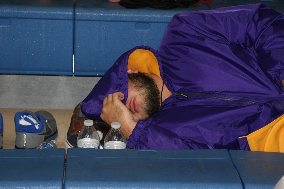 young man in a purple jacket sleeps on a bench