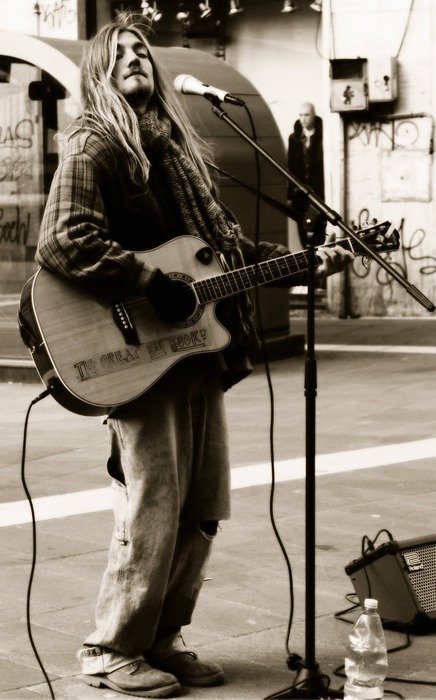 Black and white picture of a street musician with a guitar and a microphone