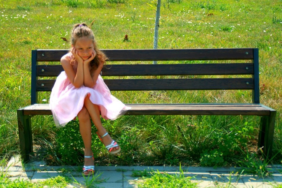 girl in a pink dress sitting on a bench