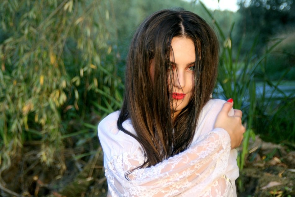 seductive girl with long hair concealing the face on the background of nature lake