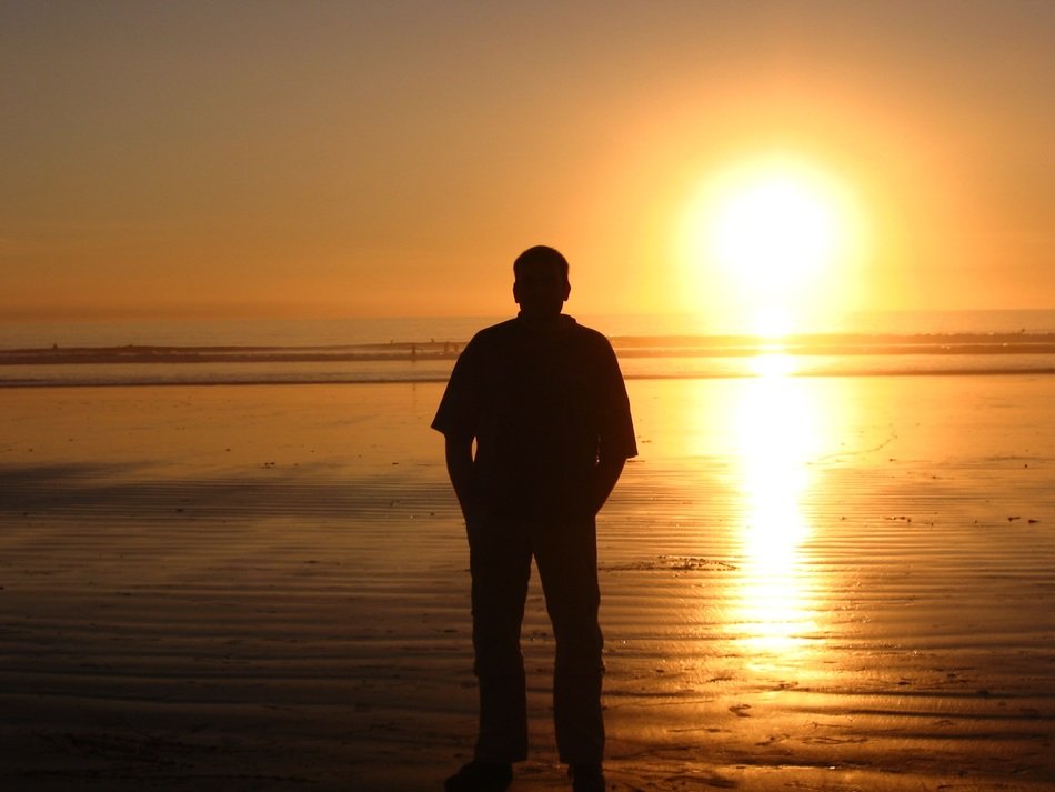 man on the background of a bright strip of sun at sunset