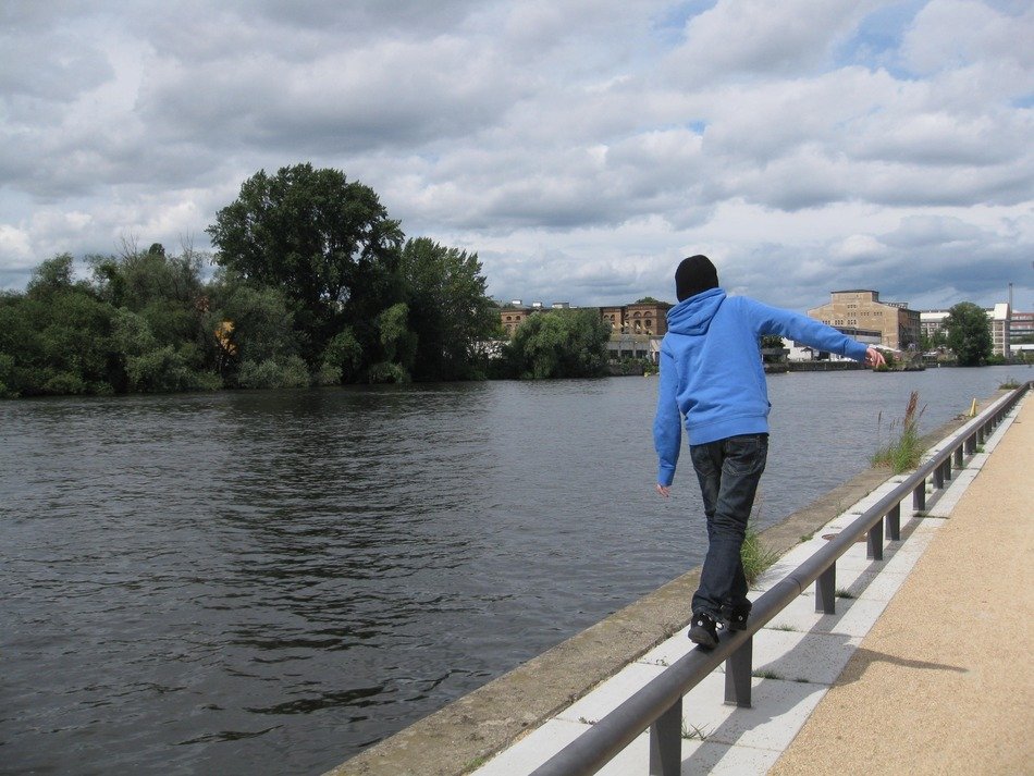 a man walks along the parapet near the river