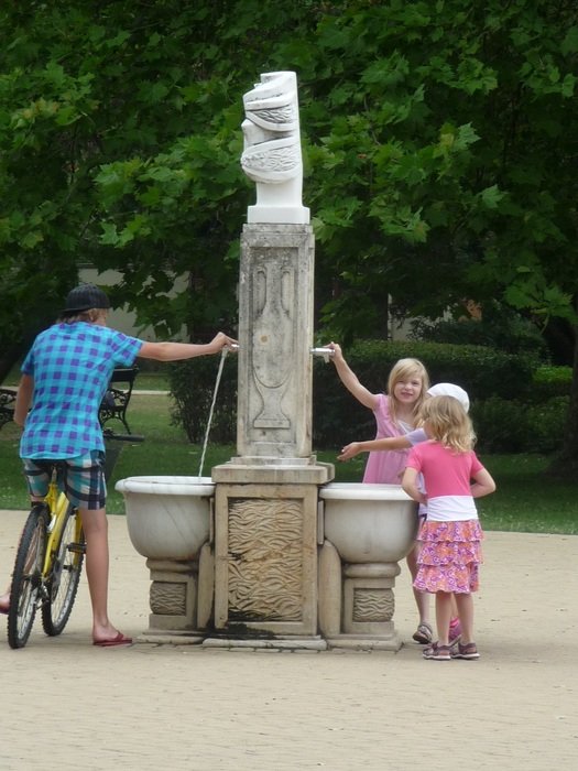 children and a man stand near the fountain