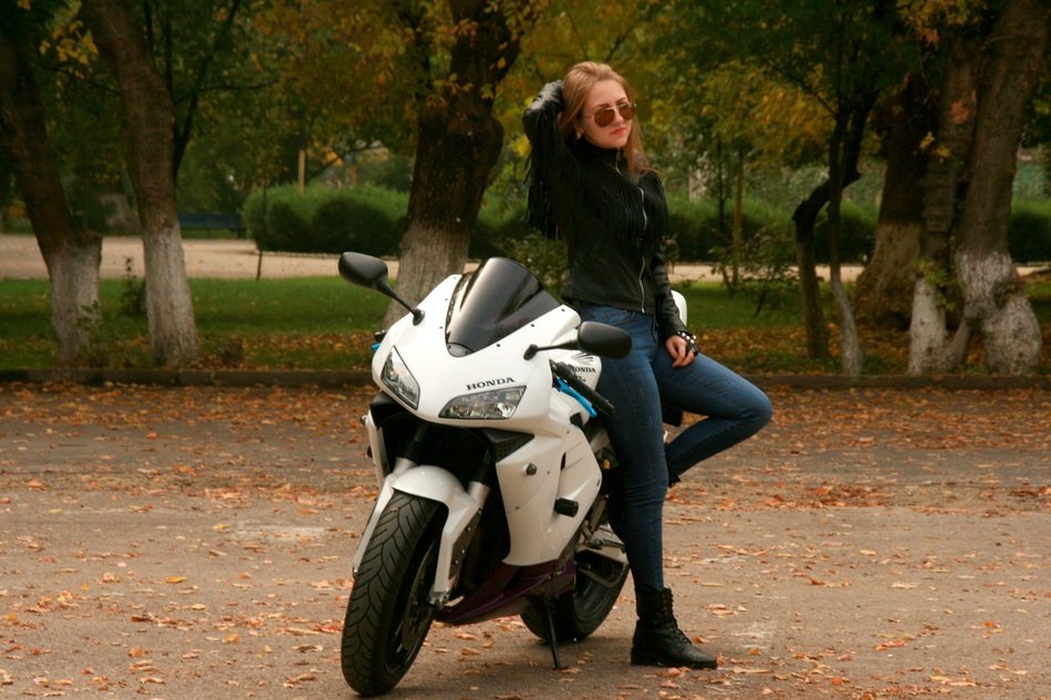 girl with blond hair in a leather jacket leaned on the bike