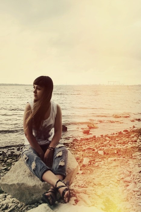 Girl is sitting on the stone near the sea