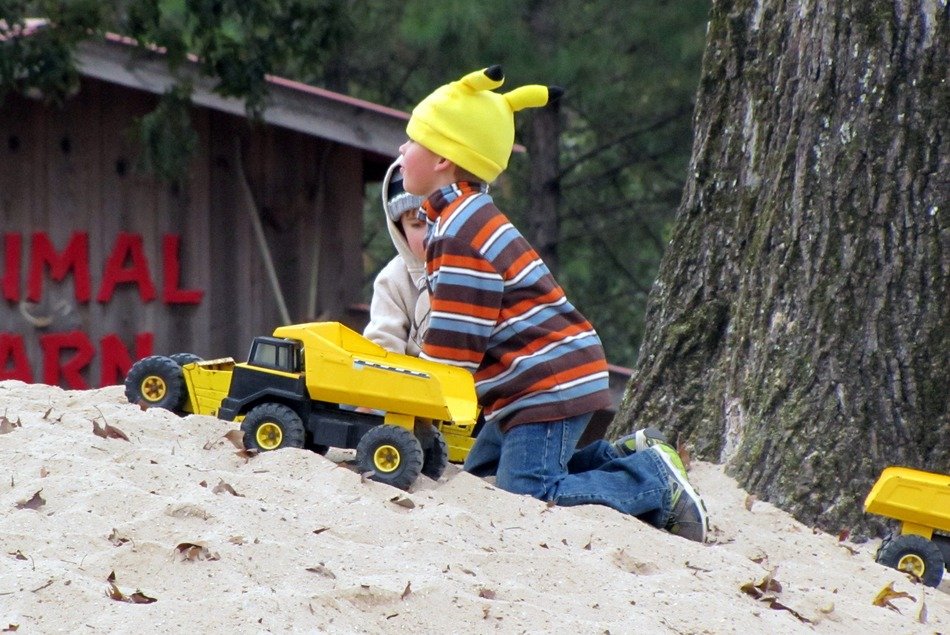 boys play with trucks on the sand