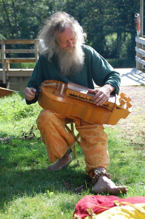 Bearded musician with an unusual stringed instrument in nature