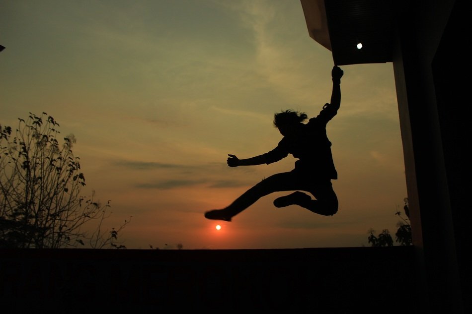 Silhouette of a man in a free jump on a sunset background