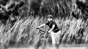 black white photo of a boy with a bicycle