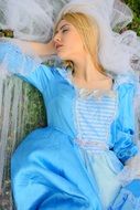 Sleeping blonde princess in a blue dress in the spring