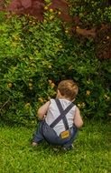 boy squatting on green grass
