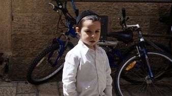 little girl stands near a bicycle