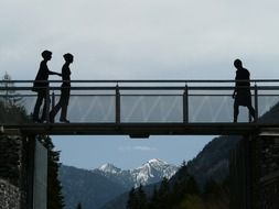 silhouettes of people on bridge