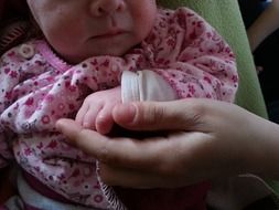 mom holds the newborn by the hand