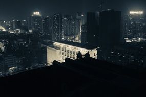 two men on the rooftop at night
