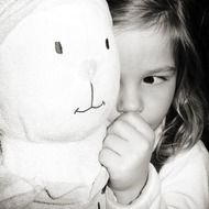 baby near a soft toy in black and white background