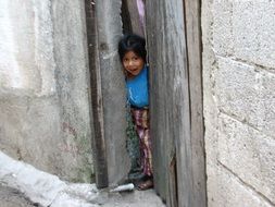 little girl peeking out the door of guatemala