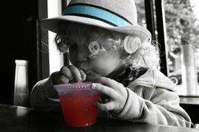 wavy hair in hat, child drinking red drink