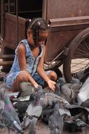 young girl sitting near pigeons