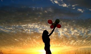 girl with balloons at sunset