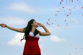 girl in a red dress on a background of flying petals
