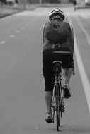 cyclist with a backpack on the road in black and white image