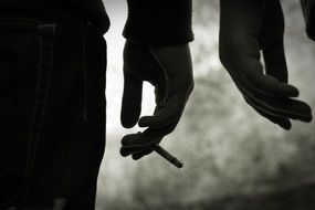 manâs hand with cigarette and another manâs hand, silhouettes