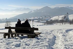 couple resting on a bench against the background of a winter landscape