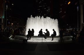 people relax at the fountain, silhouettes