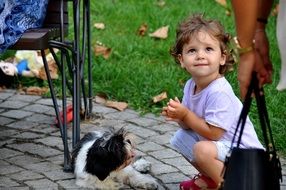 little girl playing with a puppy on the street